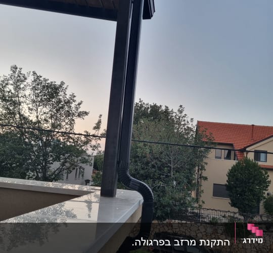 תמונה של גג עם מרזב ונוף עצים